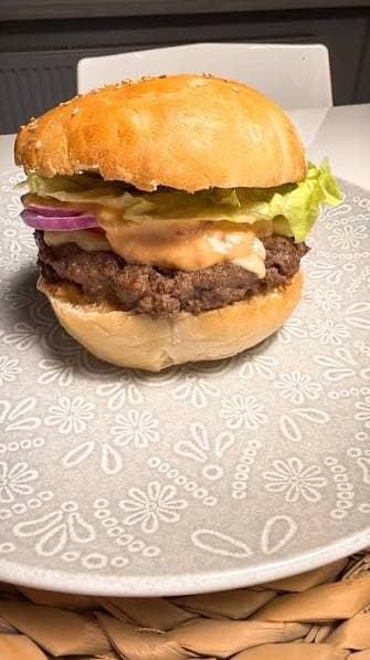 Photo d'origine d'un burger prise au smartphone sur une assiette à motifs